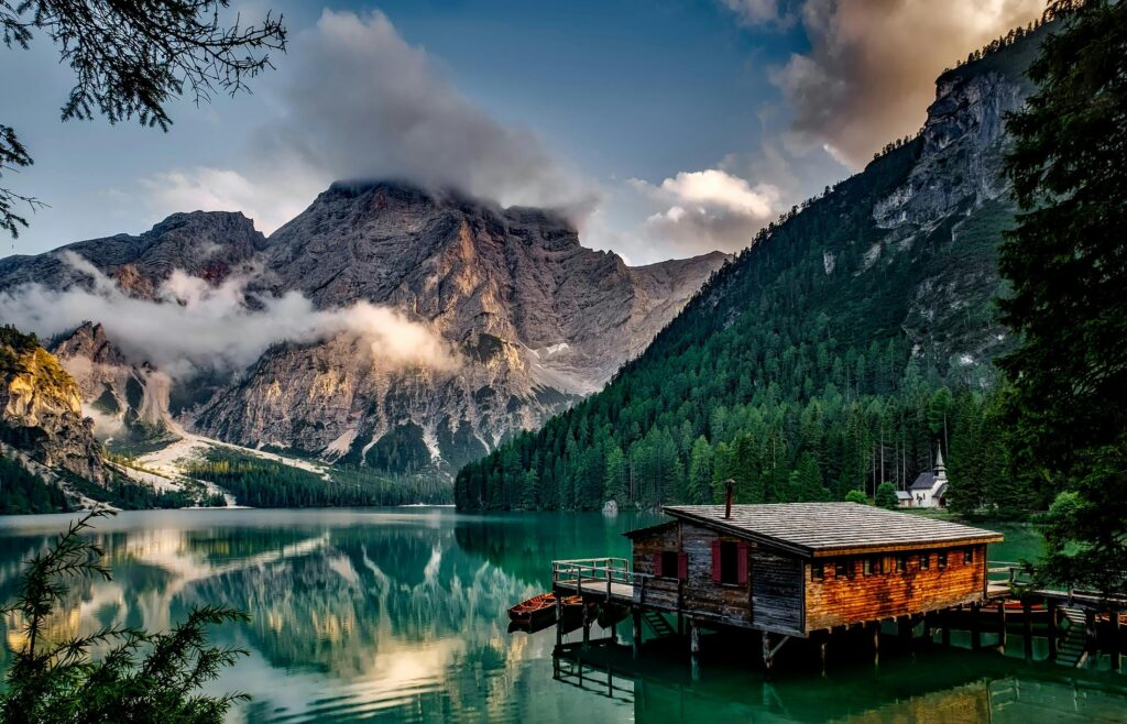 Peaceful mountain lake scene featuring a rustic boathouse and stunning reflections.